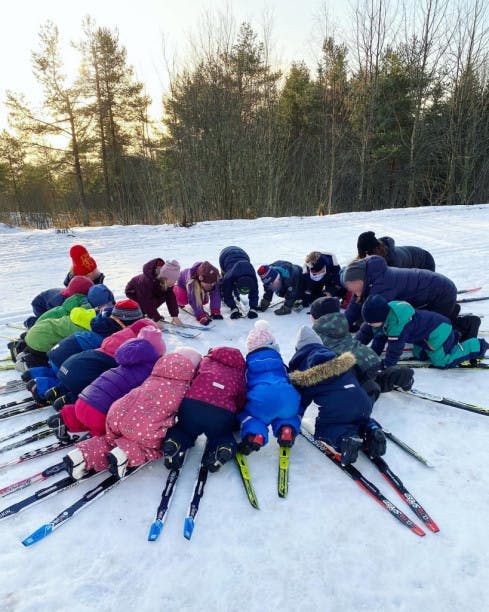 En gruppe med unger med ski som ligger i en sirkel 