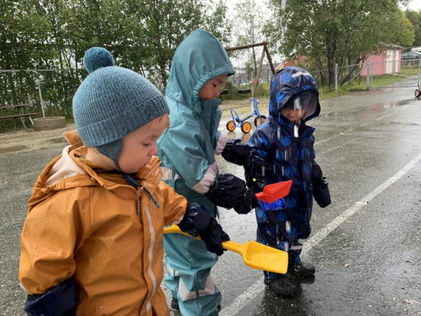 Tre unger som leker ute i regnet 