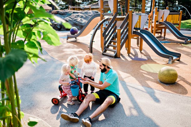 Tre unger og en voksen som leker på en lekeplass