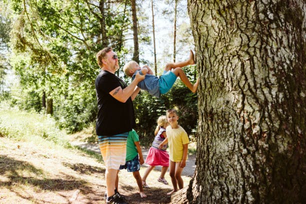 barn og en voksen leker ute ved et stort tre