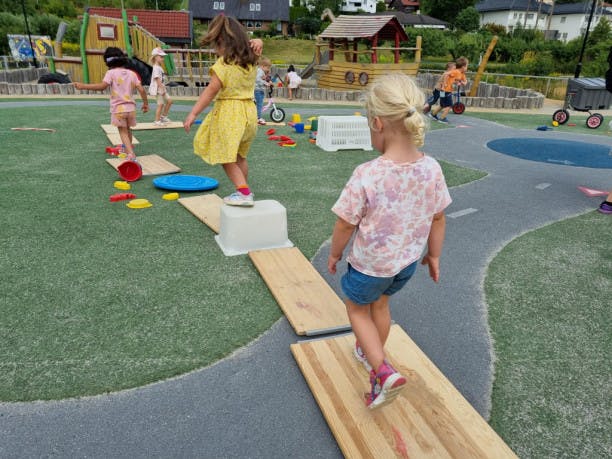 Barn som gjennomfører en hinderløype ute på lekeplassen