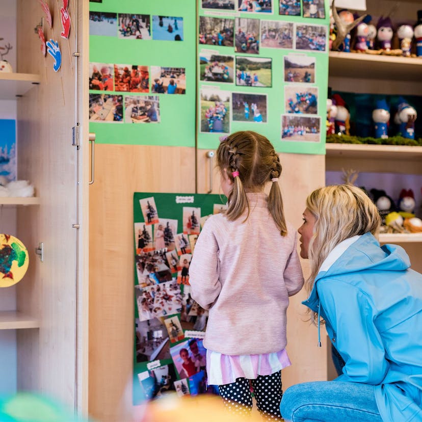 Voksen og barn ser på en vegg full av bilder